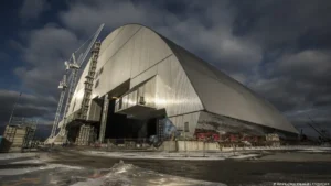 Novo Sarcófago de Chernobyl durante a sua construção. Trata-se de uma gigantesca estrutura de contenção metálica em arco prateado construída para cobrir o reator destruído., com guindastes ao lado.